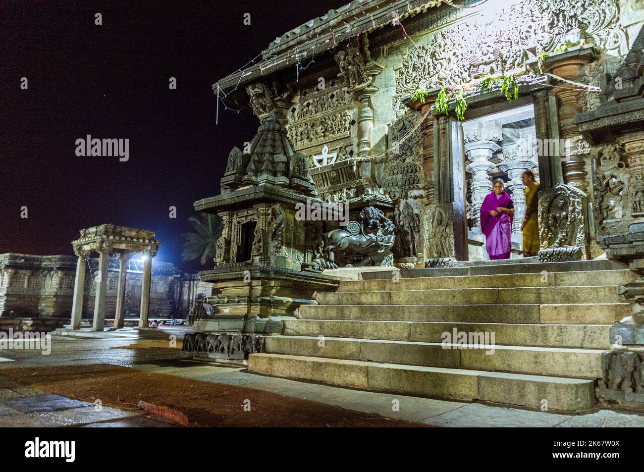 Belur, Karnataka, India: Due donne in piedi alla porta del 12th ° secolo Channakeshava Tempio di notte. Foto Stock