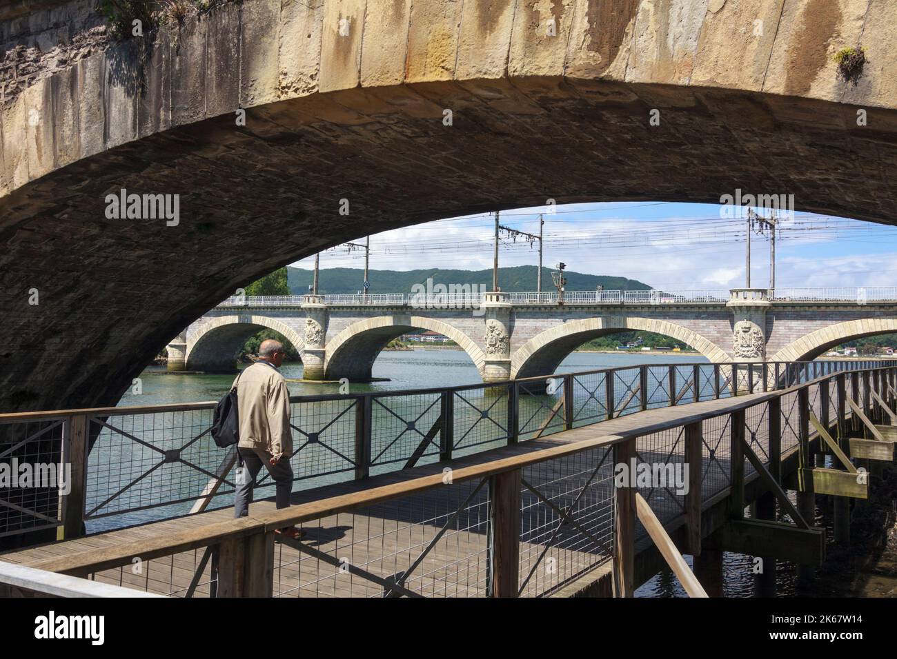 Hendaye, Paesi Baschi francesi, Francia : Un uomo cammina sotto il ponte internazionale di Santiago sul fiume Bidasoa che collega Spagna e Francia. Foto Stock