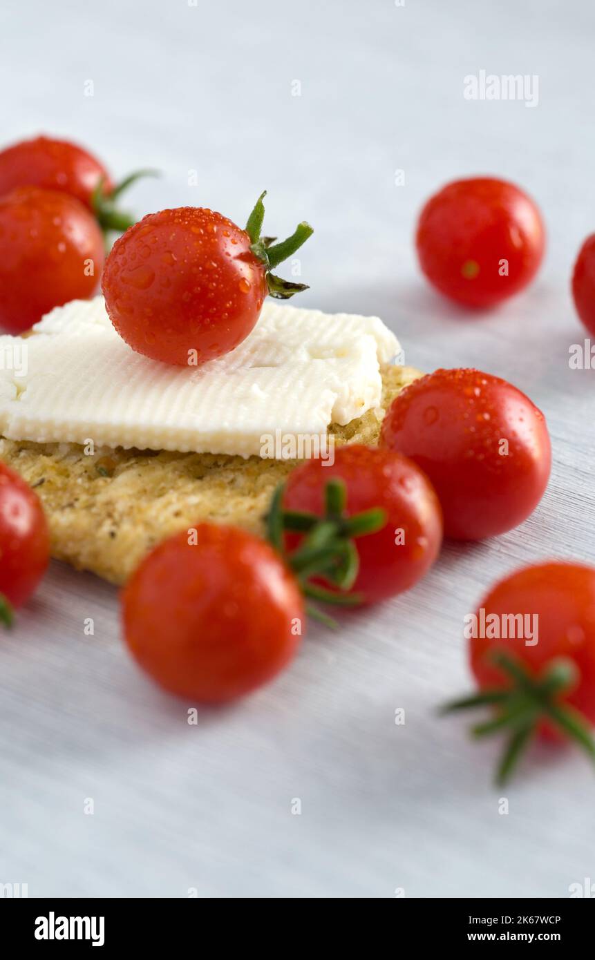 Macro immagine dei pomodori rossi del bambino con cracker e formaggio verticale Foto Stock