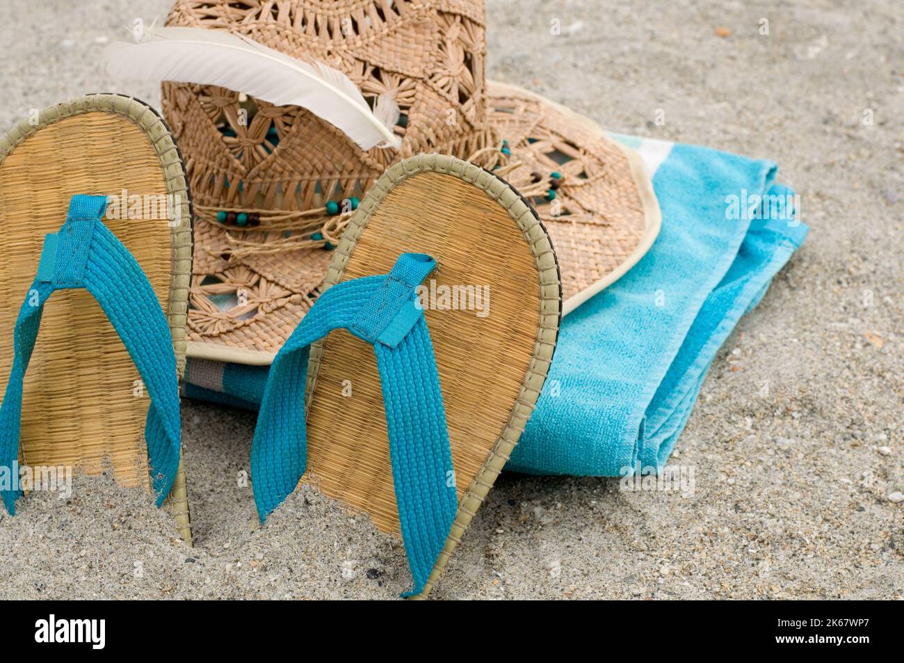 Asciugamano blu, sandali e cappellino di paglia nella sabbia orizzontale Foto Stock