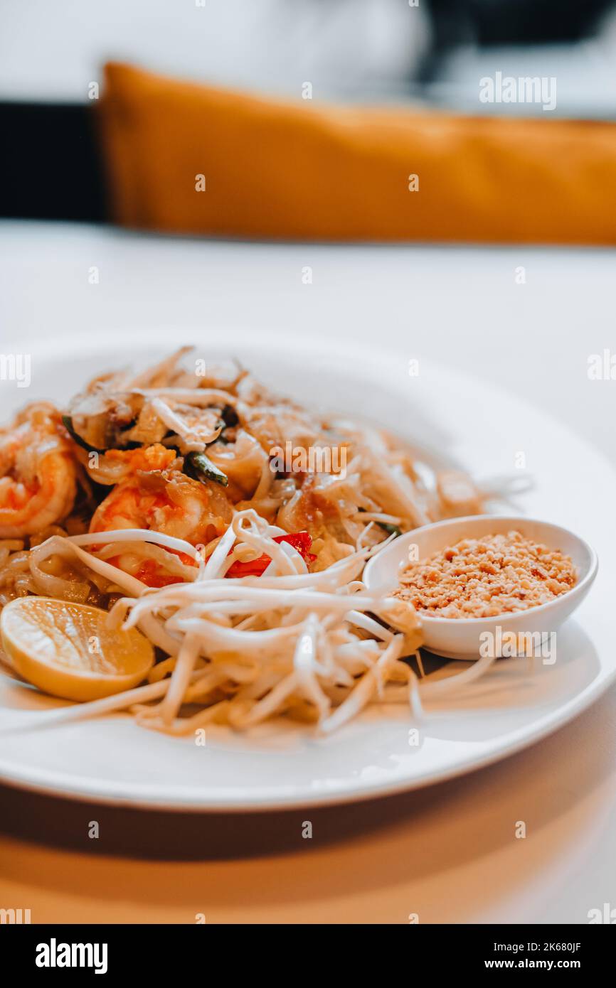 Cibo tradizionale Tailandese Pad noodle tailandesi con gamberi, germogli freschi e una fetta di limone. Dettagli primo piano. Verticale Foto Stock