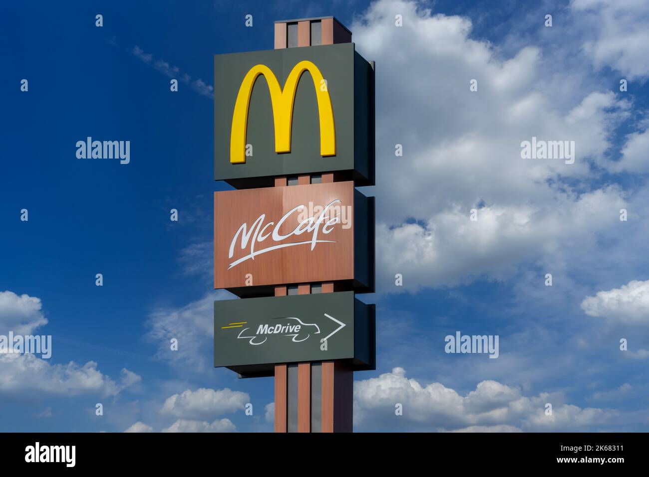 Savigliano, Italia - 16 giugno 2022: Cartello McDonald's con logo McCafe e McDrive su cielo blu con nuvole bianche. La McDonald's Corporation è la società del mondo Foto Stock