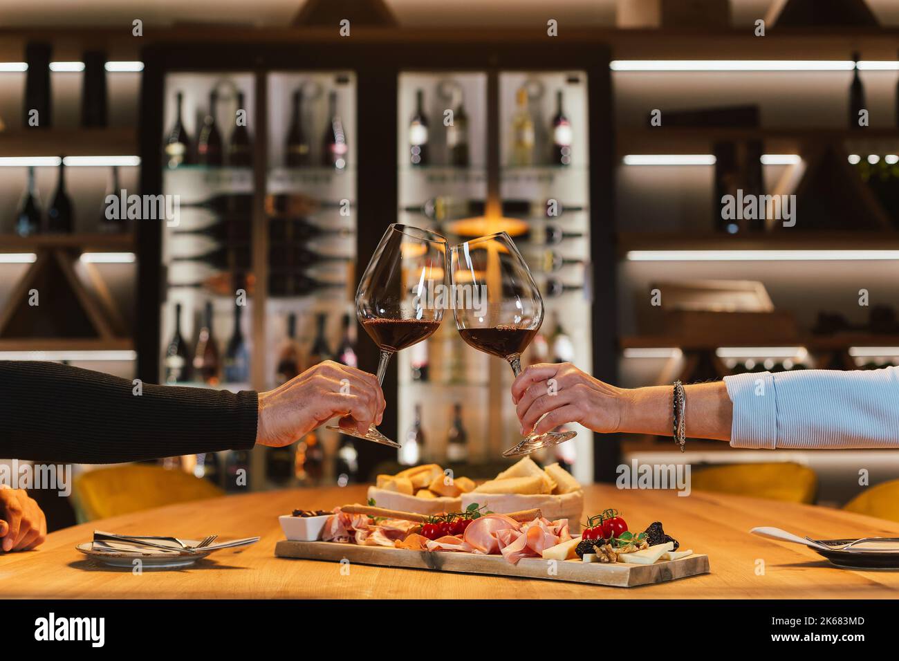 Una coppia romantica si siede l'una di fronte all'altra al tavolo da pranzo nella sala dei vini, si siede davanti ai bicchieri e sorseggia vino bianco Foto Stock