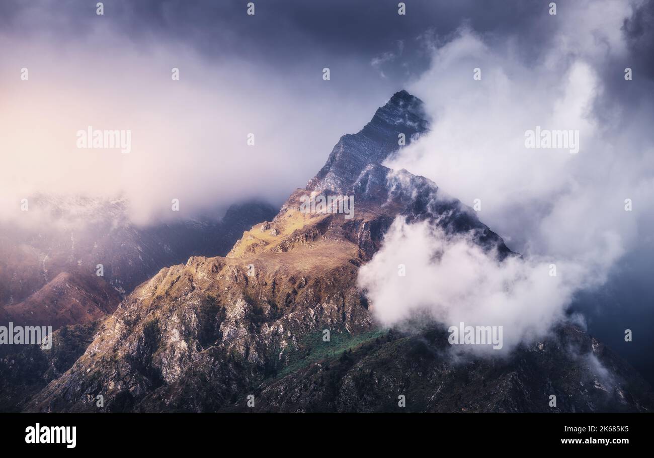 Picco di montagna in nubi basse al tramonto colorato in Nepal Foto Stock