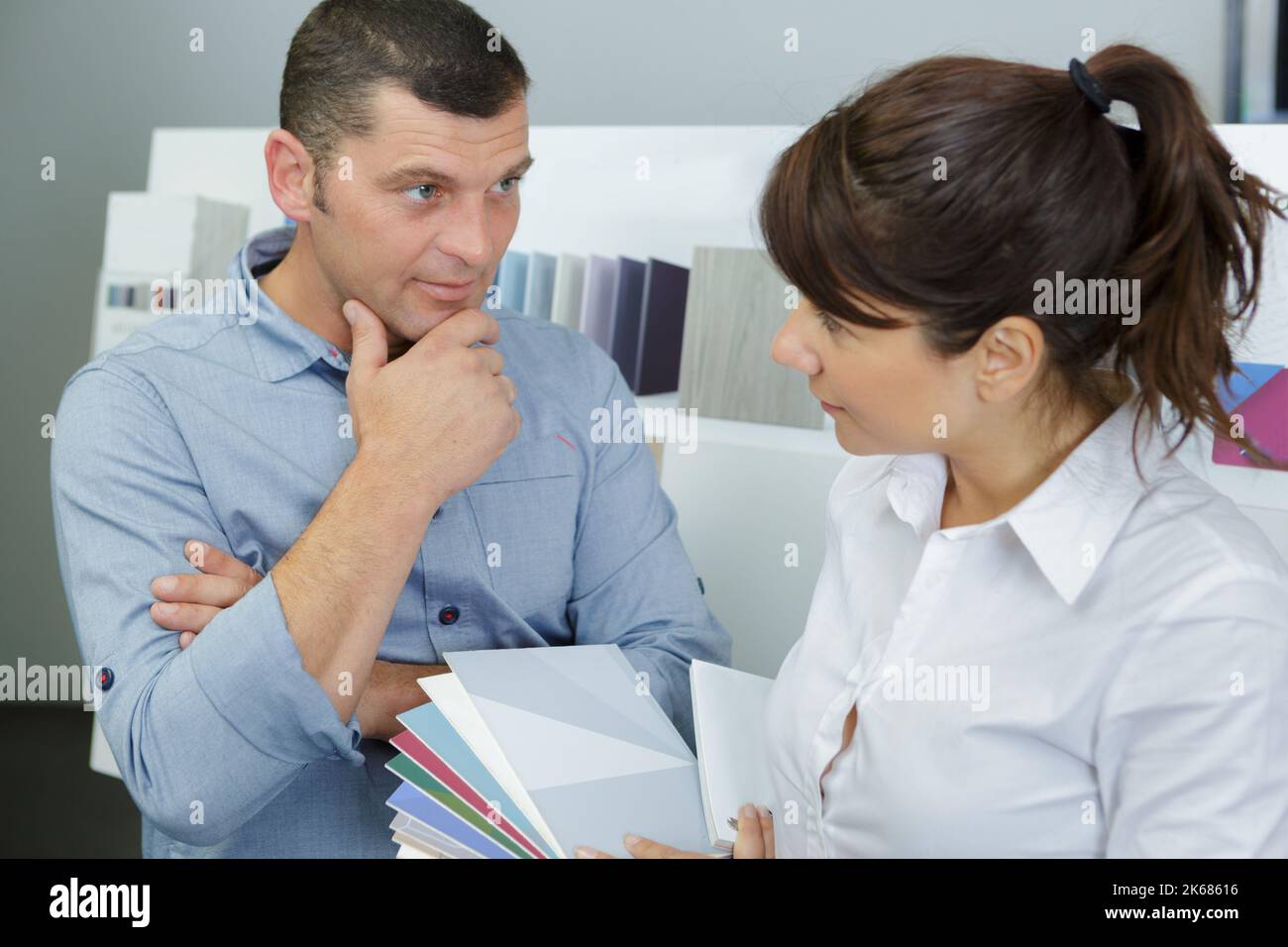 assistente alle vendite che guarda le opzioni di colore con il cliente Foto Stock