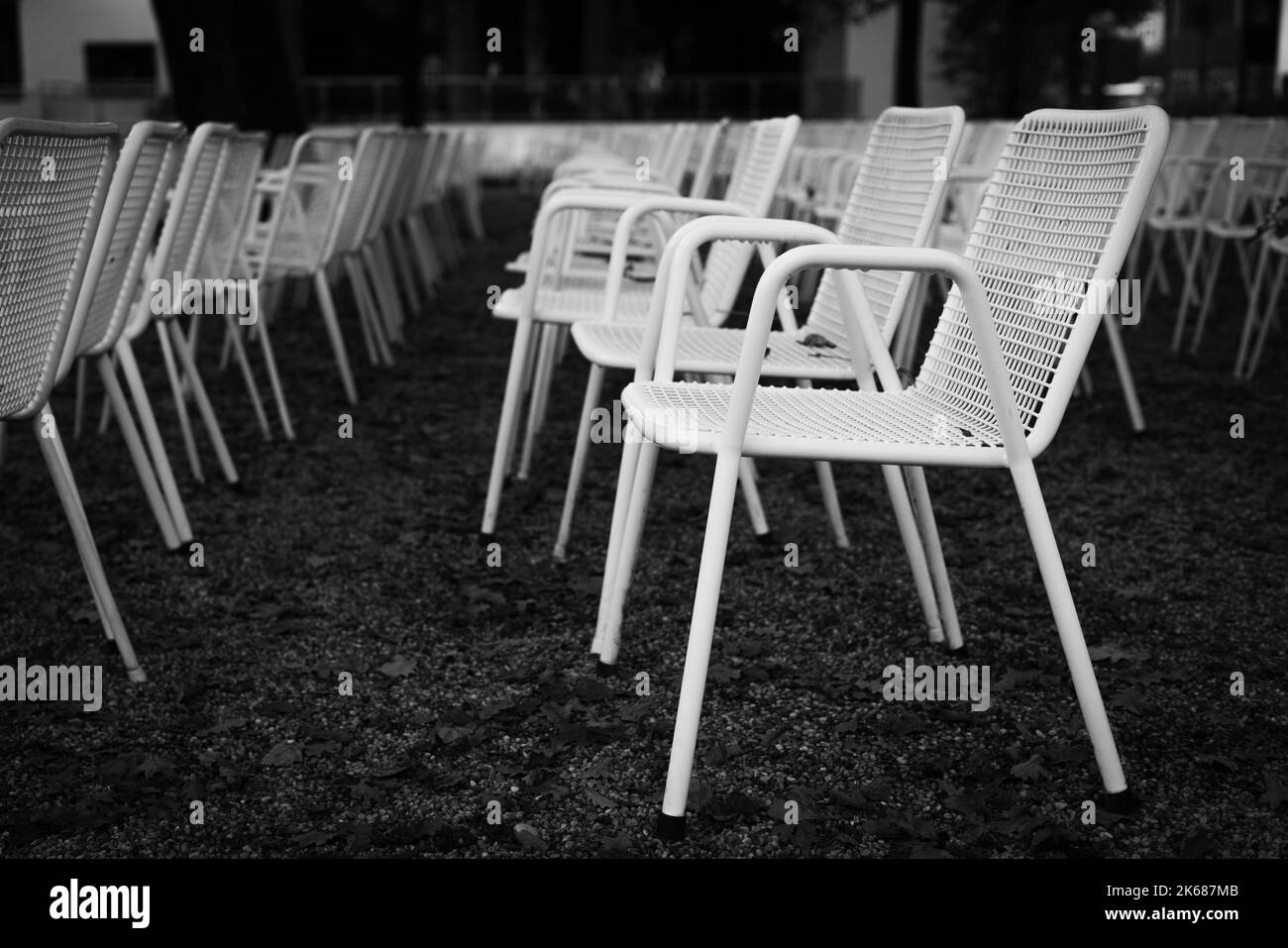 File di sedie da giardino in metallo bianco davanti a un palco all'aperto. Foto Stock