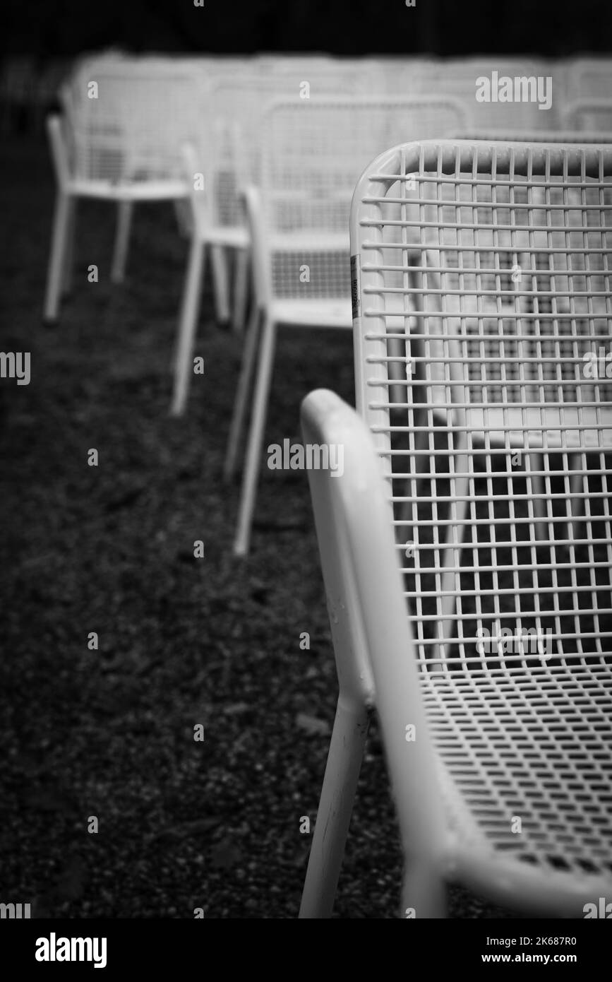 File di sedie da giardino in metallo bianco davanti a un palco all'aperto. Foto Stock