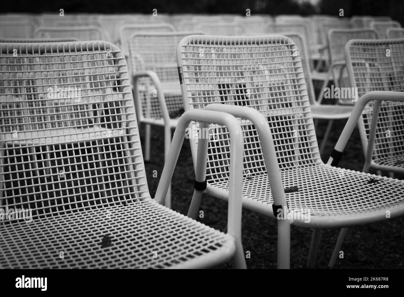File di sedie da giardino in metallo bianco davanti a un palco all'aperto. Foto Stock
