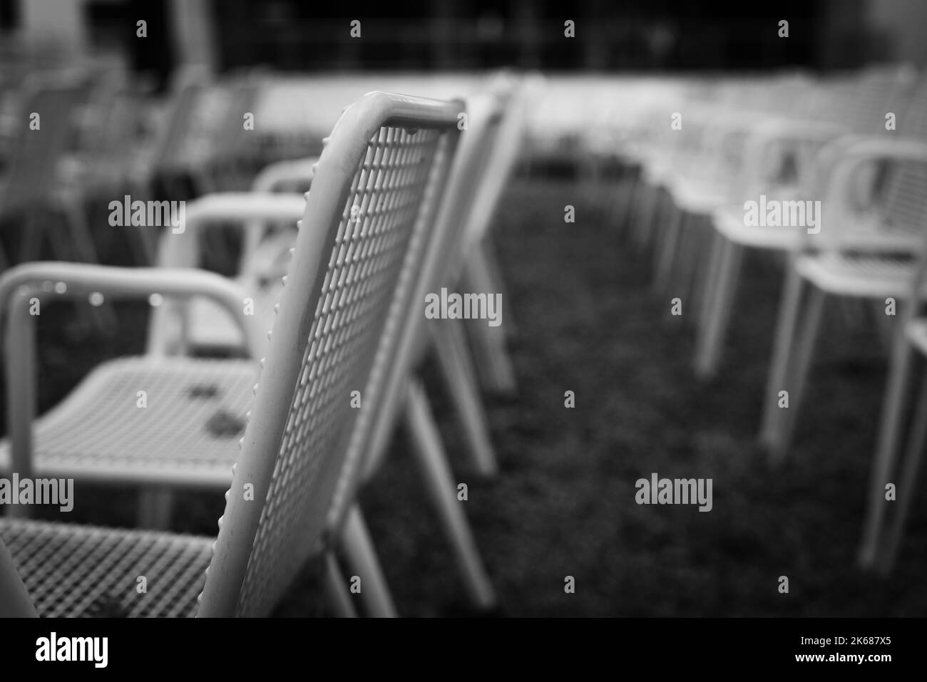 File di sedie da giardino in metallo bianco davanti a un palco all'aperto. Foto Stock
