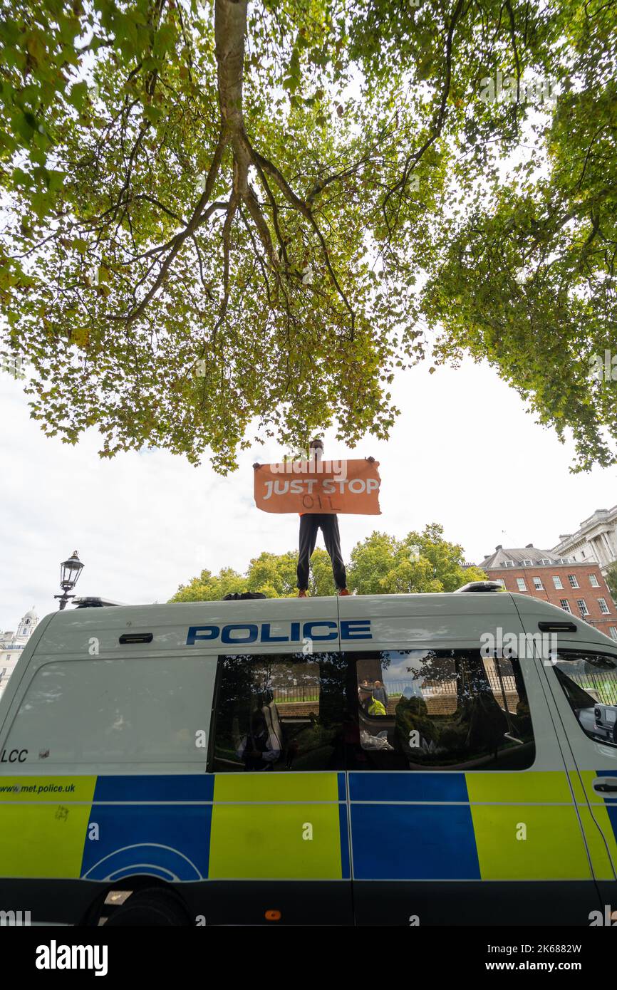 Due sostenitori di Just Stop Oil sono saliti sulla cima di un pulmino della polizia metropolitana fuori da Horse Guards Road a Londra mercoledì (12 ottobre) in un periodo in corso Foto Stock