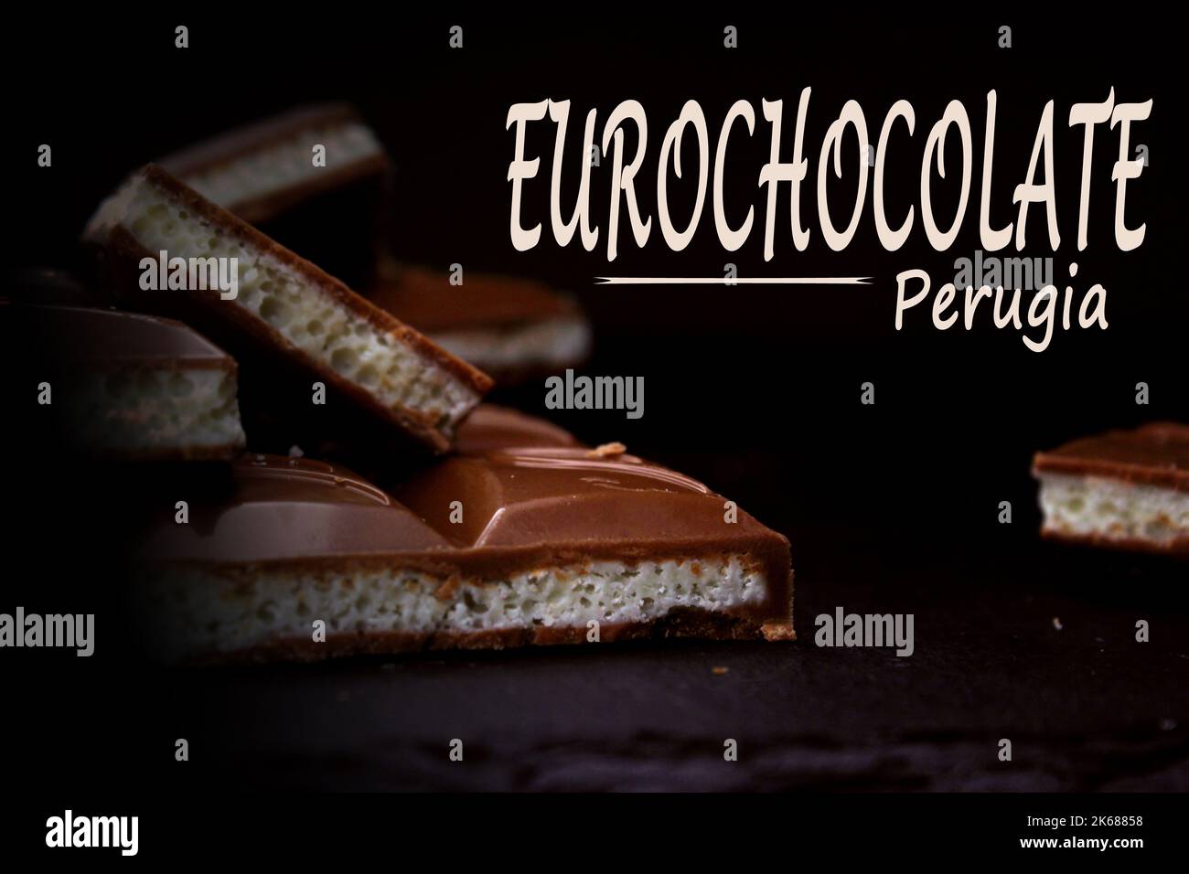 Pezzi di cioccolato aerato al latte primo piano su sfondo scuro con un'iscrizione. Il concetto di Perugia Chocolate Festival. Foto Stock