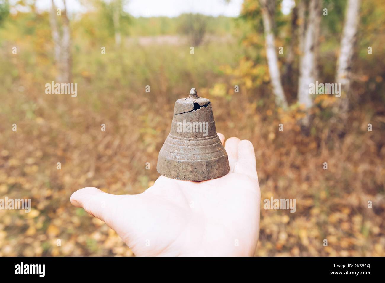 Una vecchia campana, assemblata con un metal detector, sullo sfondo di una foresta autunnale. Il mio hobby è la ricerca di oggetti d'antiquariato Foto Stock