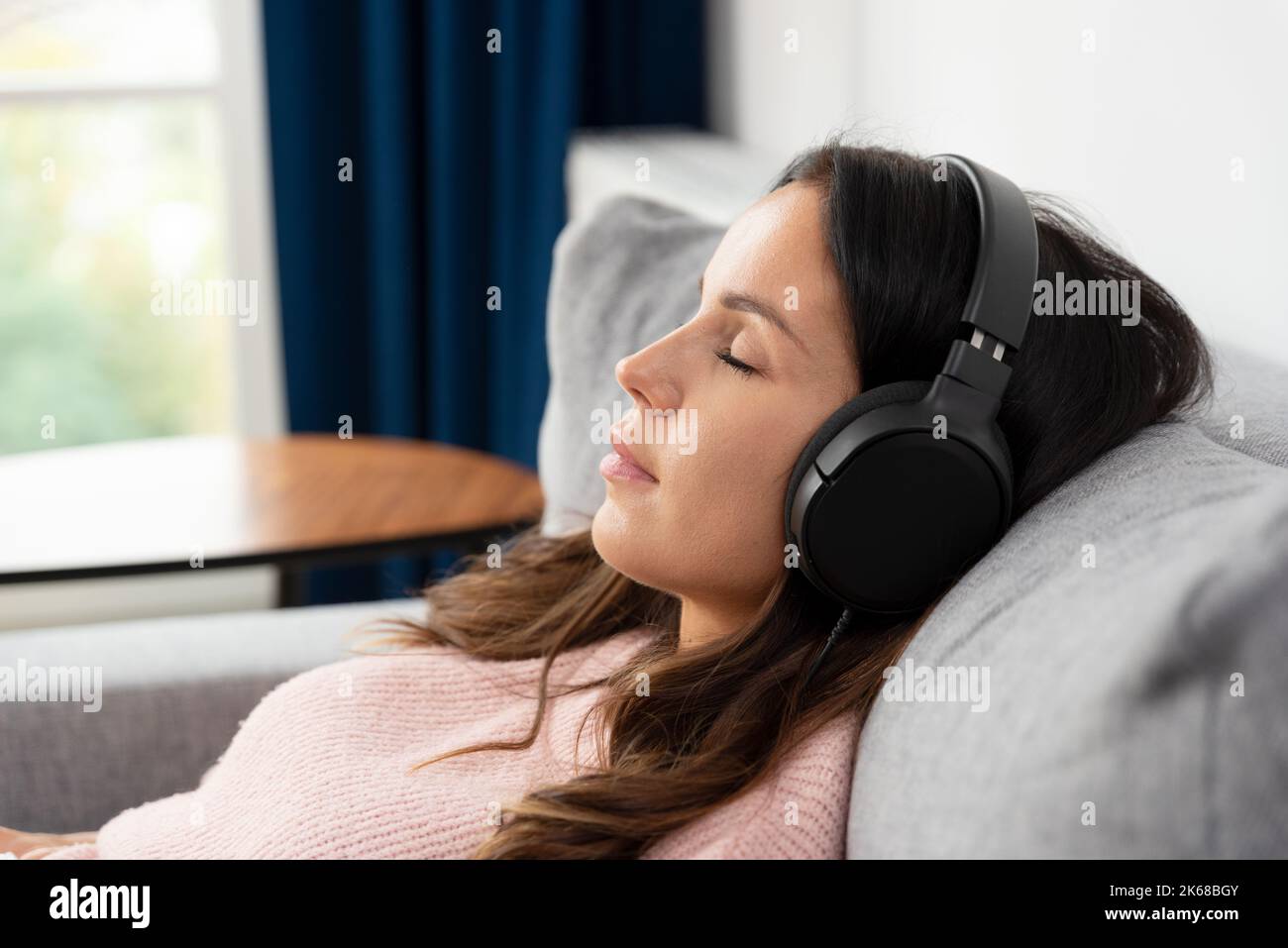 Donna che ascolta la musica con le cuffie e si rilassa a casa Foto Stock