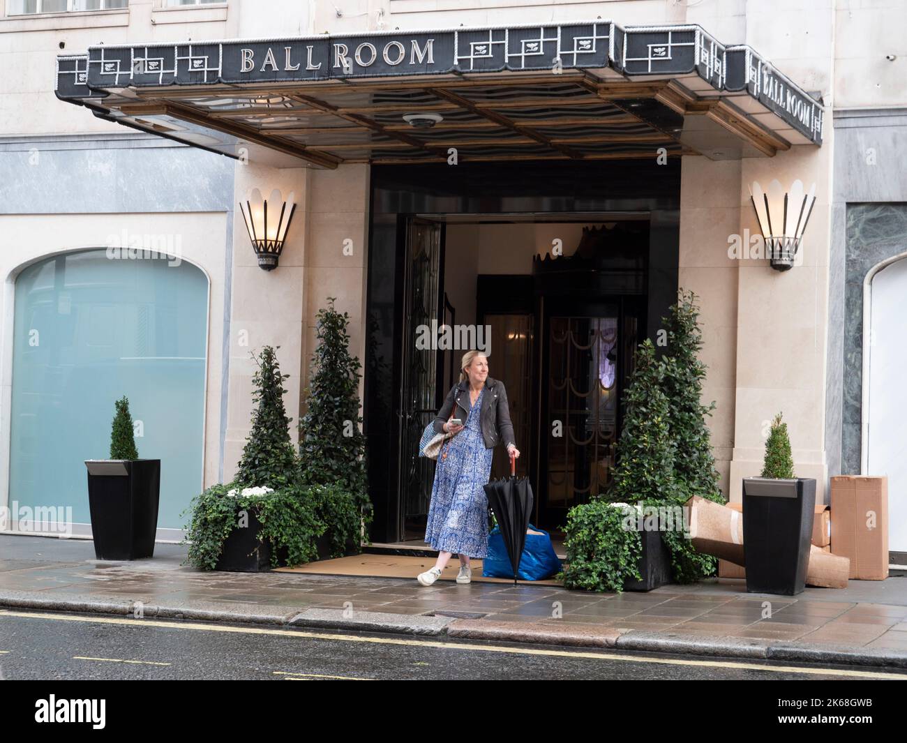 In attesa di un taxi sotto la pioggia fuori dalla sala da ballo Claridges, Mayfair, Londra, Regno Unito Foto Stock
