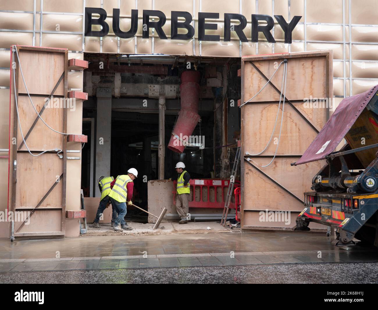 Mayfair, Londra, Regno Unito, temporanea accatastamento di fronte al negozio Burberry durante la ristrutturazione, con costruttori e appaltatori che riempiono il salto di spazzatura Foto Stock