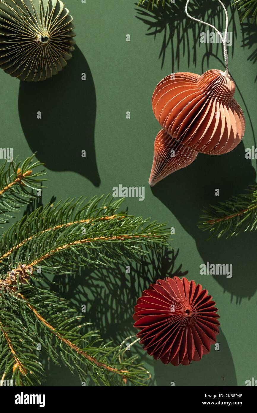 Decorazioni natalizie in carta e rami di abete su sfondo verde con spazio copia. Foto Stock