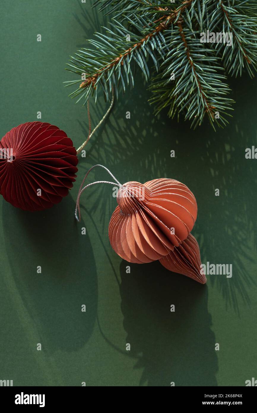 Decorazioni natalizie in carta e rami di abete su sfondo verde con spazio copia. Foto Stock