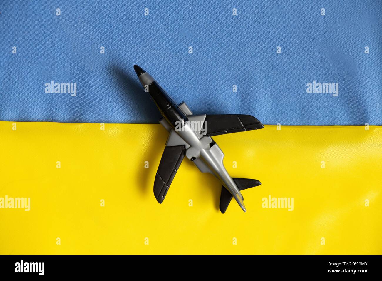 Un aereo giocattolo per bambini giace sulle bandiere nazionali dell'Ucraina, la guerra in Ucraina, un cielo chiuso Foto Stock