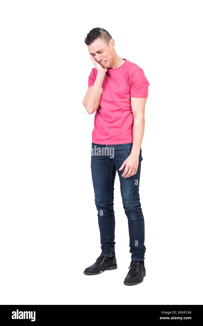 Triste giovane uomo che tocca il viso e piange in studio Foto Stock