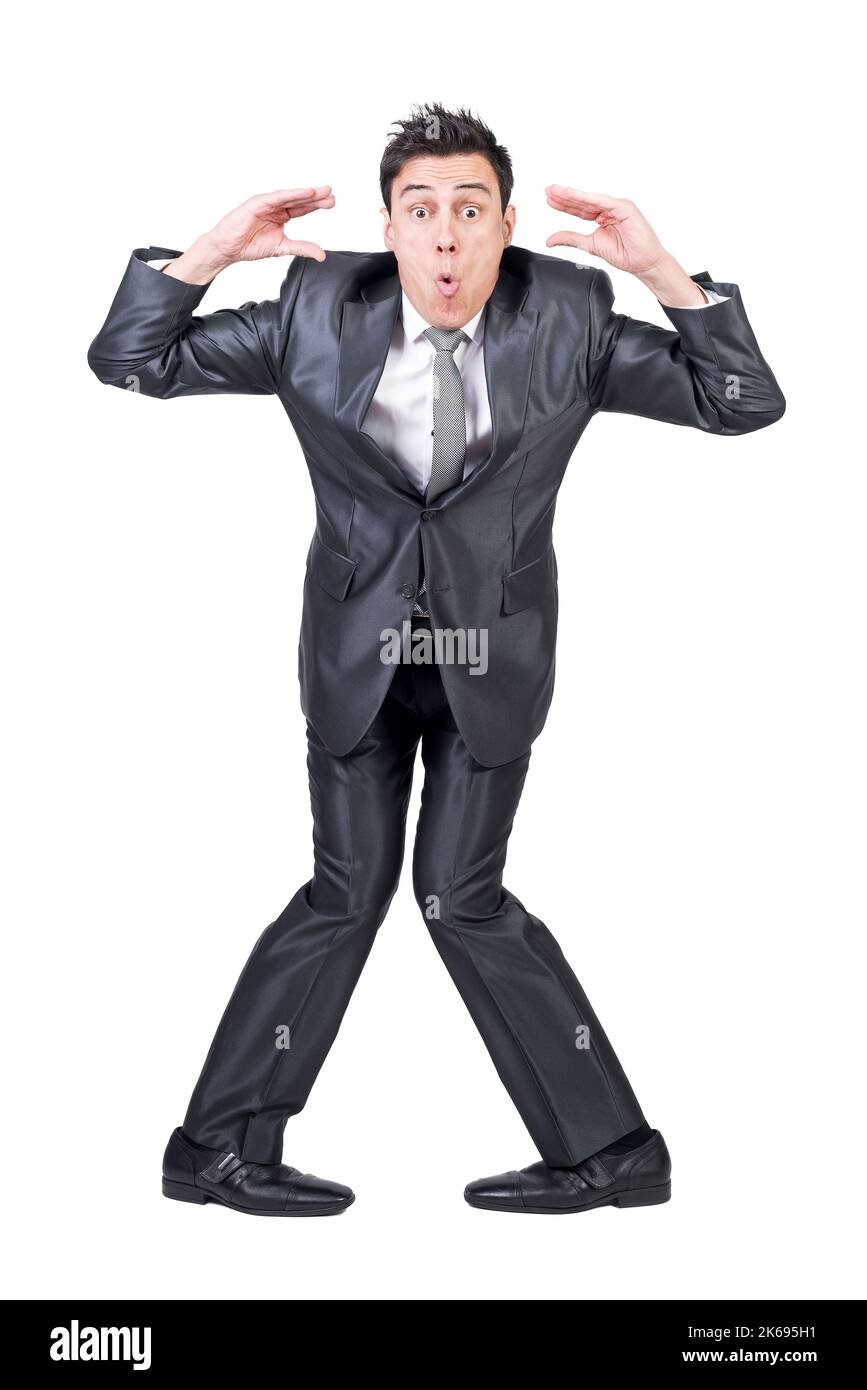 Tutta la lunghezza del giovane impiegato divertente maschio con i capelli scuri che fanno la faccia e gesturing contro lo sfondo bianco Foto Stock