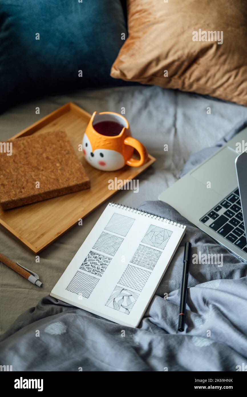 Doodling per principianti, come iniziare Doodle. Doodle disegni semplici schizzo in notebook vicino al computer portatile e tè caffè tazza in cattivo casa. Foto Stock