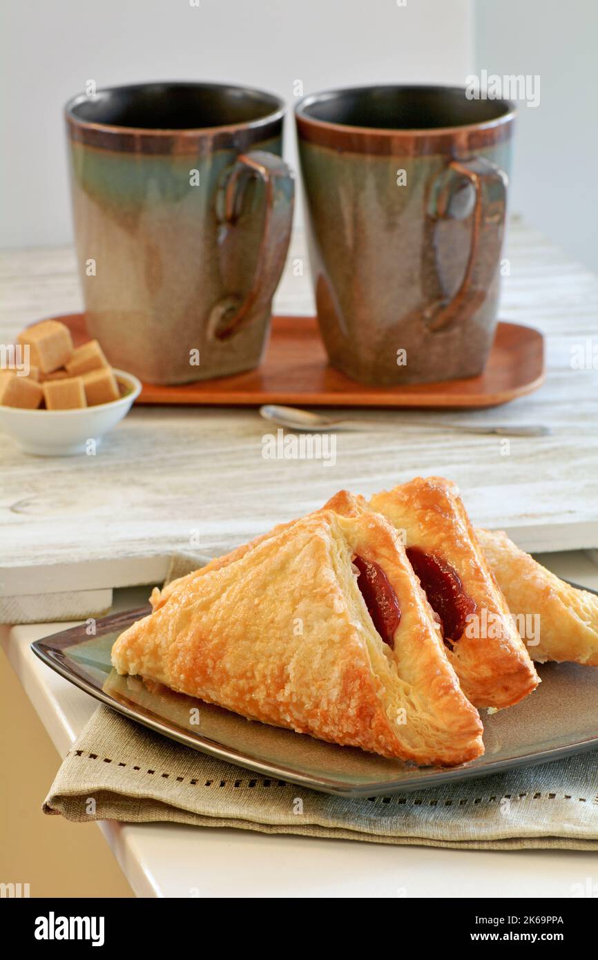 Turnover di lamponi appena sfornati con caffè in formato verticale. Gustoso spuntino pausa caffè. Foto Stock