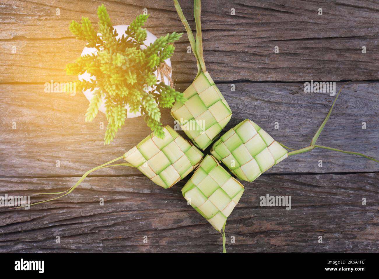 Ketupat (riso Dumpling) e riso su sfondo di legno. Il Ketupat è un rivestimento di riso naturale realizzato con giovani foglie di cocco per cucinare il riso durante l'eid Mubar Foto Stock