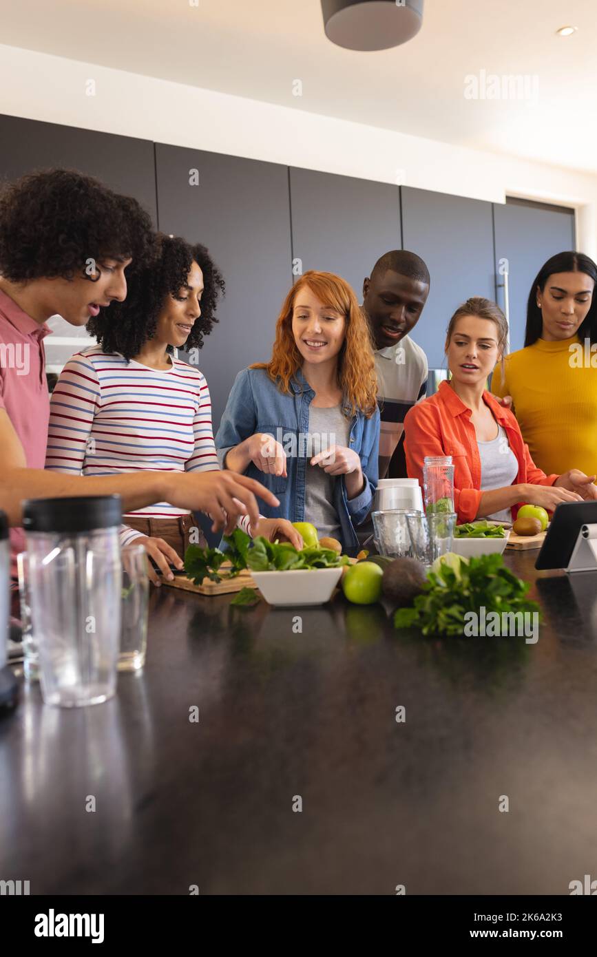 Felici amici diversi che cucinano insieme e sorridono in cucina Foto Stock