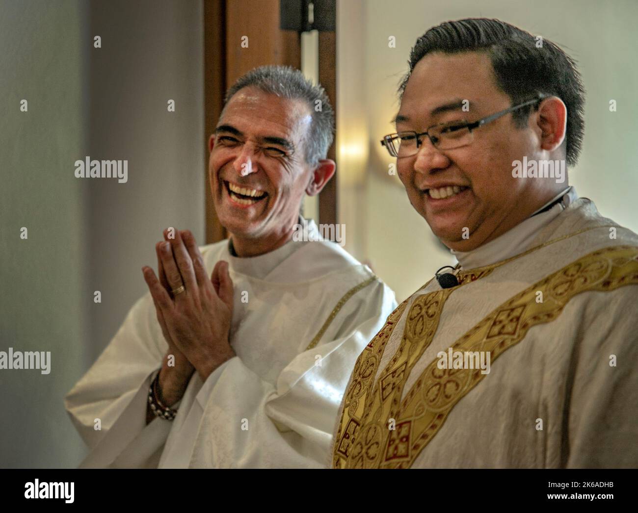 Il diacono ispanico e il prete vietnamita cattolico in camera arrivano per la messa in una chiesa cattolica della California meridionale. Foto Stock