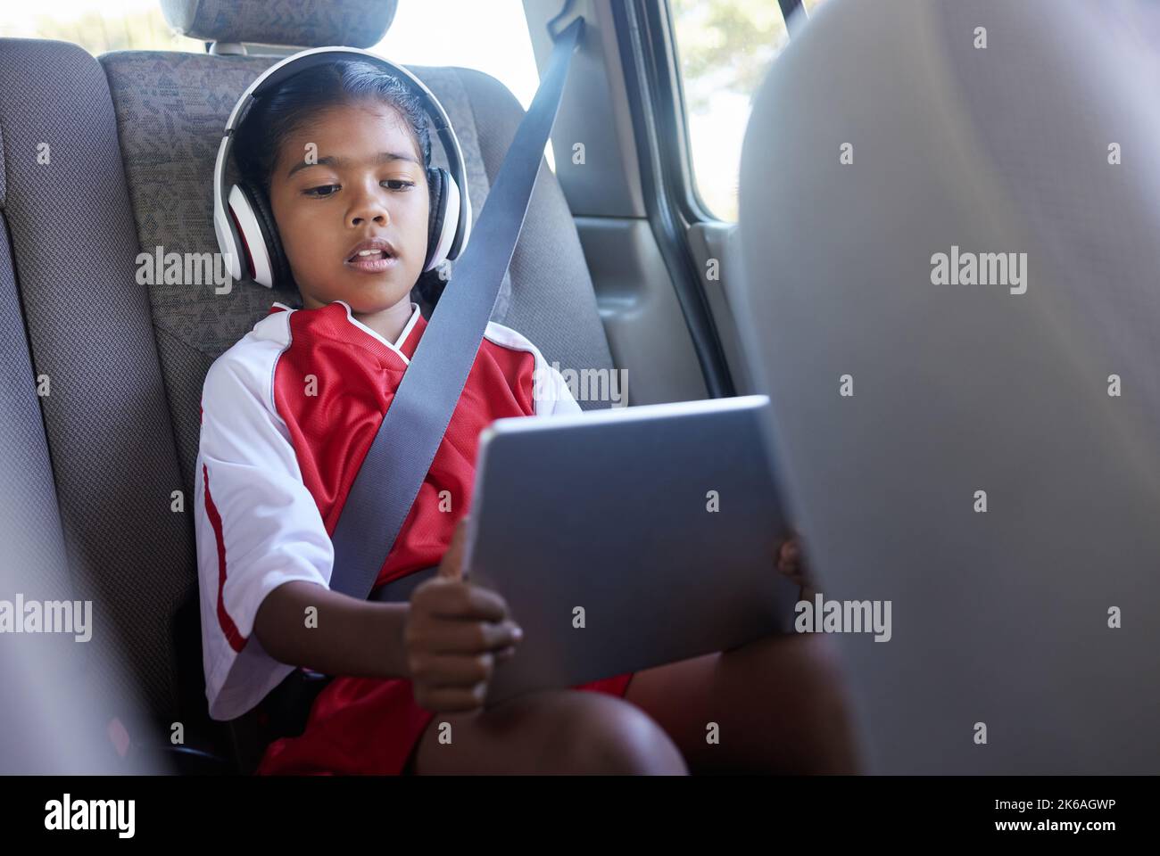 Sport, viaggio in auto e relax dei bambini con un tablet durante il viaggio verso il calcio pratica mentre lo streaming di video, guardare film o giocare a giochi online. Trasporto, SUV Foto Stock