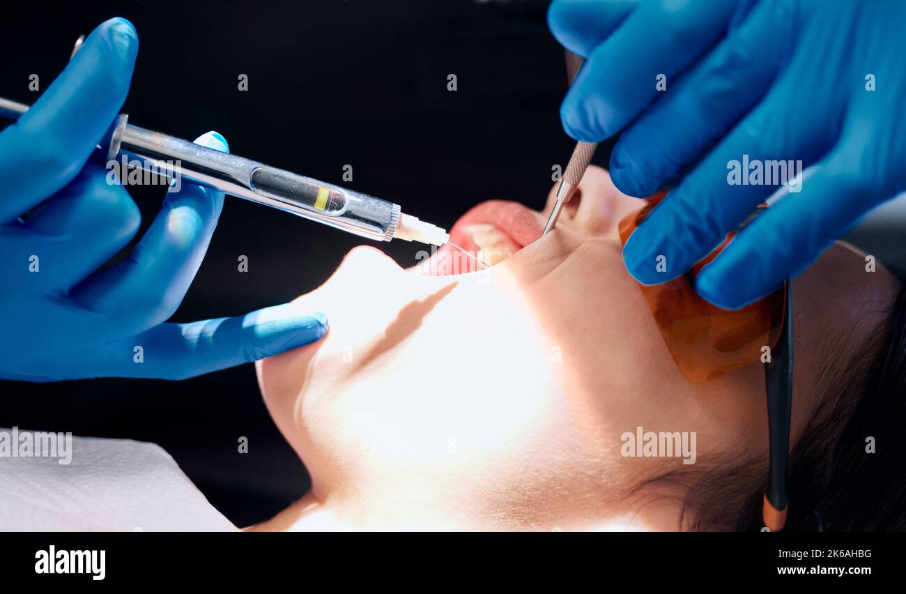 Appena un pizzico piccolo. Una donna che riceve un'iniezione all'ufficio dei dentisti. Foto Stock