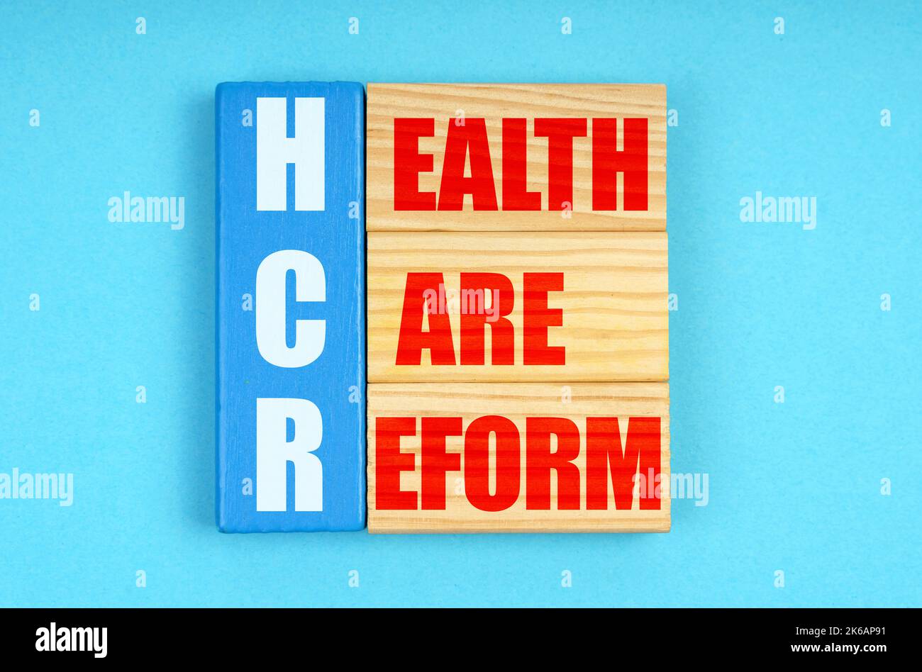 Concetto di medicina. Su sfondo blu, targhe di legno con l'iscrizione - RIFORMA SANITARIA Foto Stock