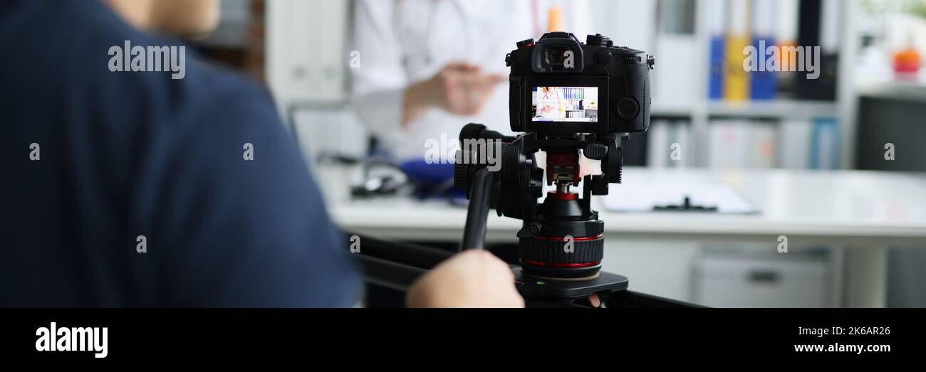 Fotografo che filma il medico con la fotocamera utilizzando il cavalletto e il primo piano del cursore Foto Stock