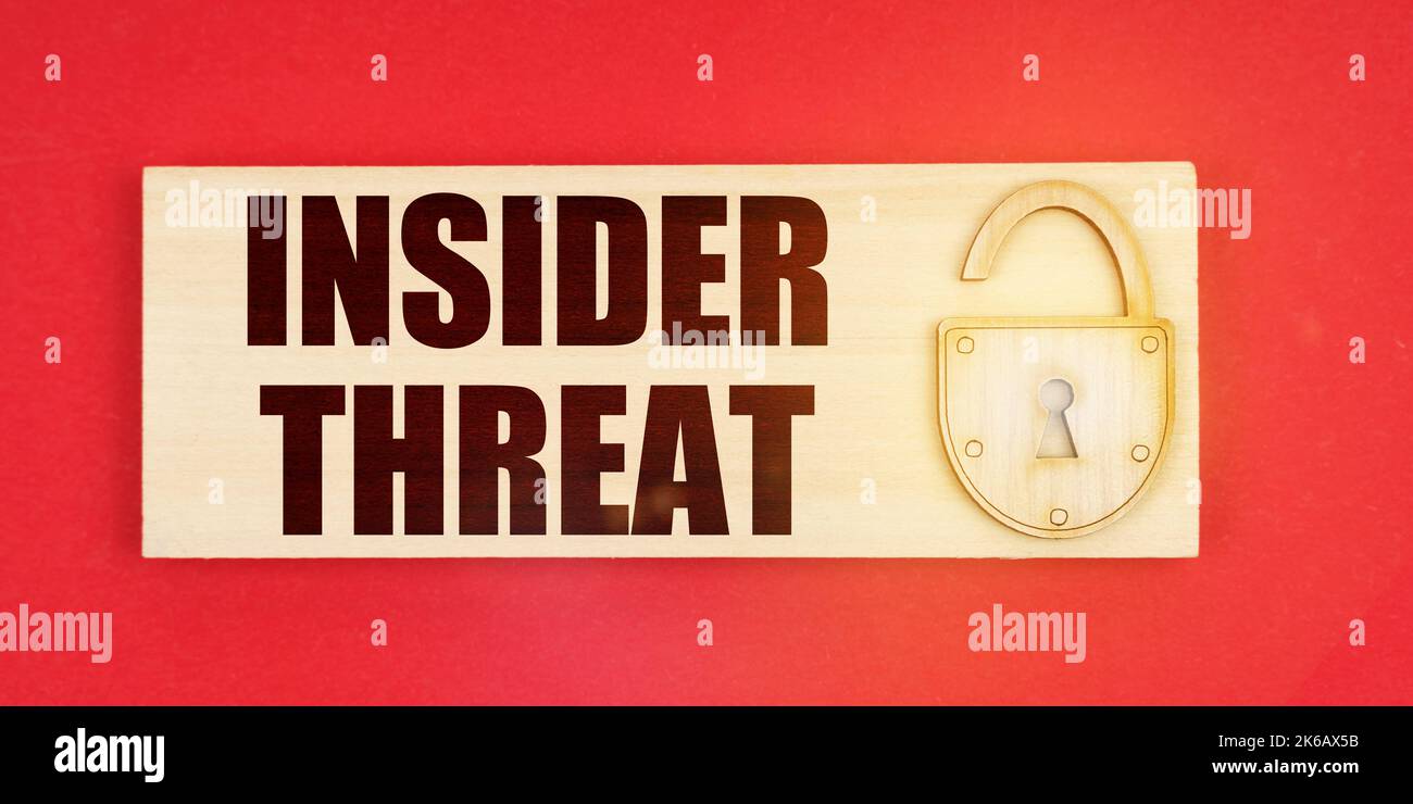 Concetto aziendale. Su uno sfondo rosso vi è una piccola targa con una serratura e un'iscrizione - INSIDER MINACCIA Foto Stock
