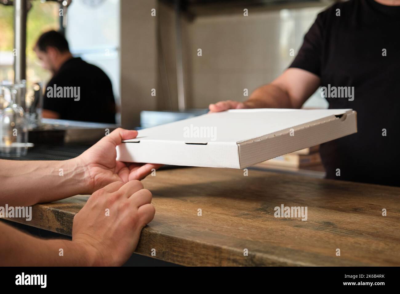 Cameriere irriconoscibile che dà la scatola della pizza ad un cliente senza volto. Foto Stock