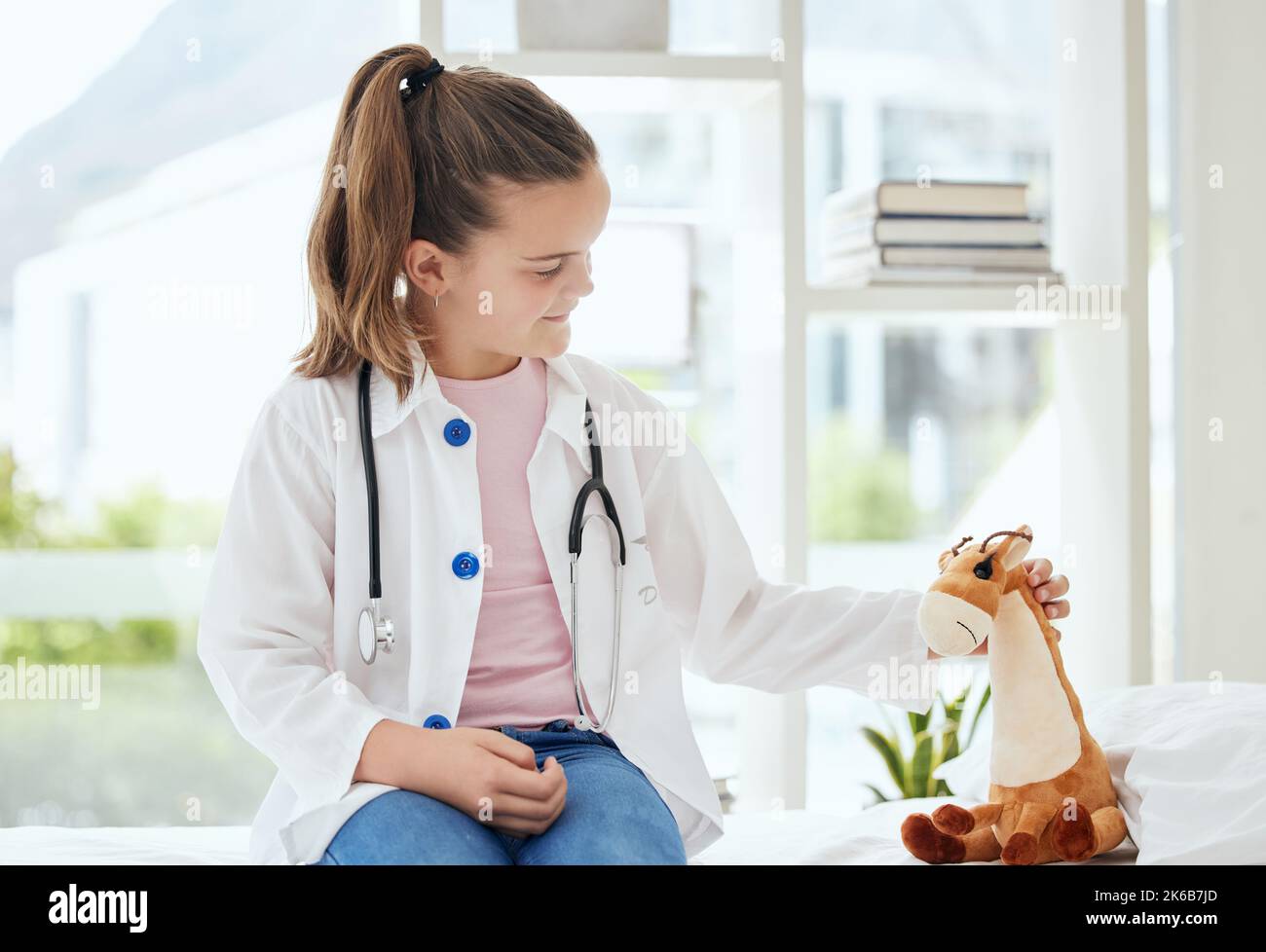 Youre tutto meglio ora. Una bambina che finge di essere un medico mentre esamina il suo animale farcito a casa. Foto Stock