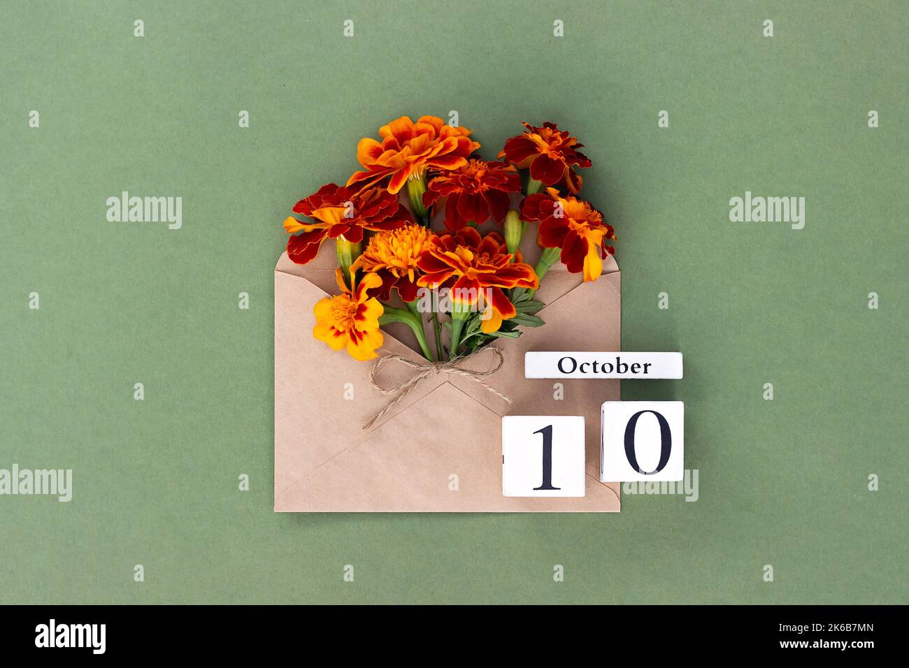 Ottobre 10. Bouquet di fiori d'arancio in busta artigianale e data di calendario su sfondo verde. Concetto minimo Ciao autunno. Modello per il progetto, gr Foto Stock