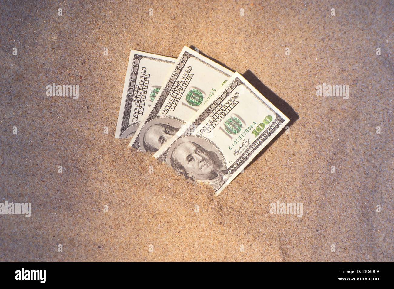 I soldi dolari mezzo coperto di sabbia giacciono su spiaggia da vicino. Trecento dollari sepolti in sabbia sul mare o oceano spiaggia concetto finanziamento soldi vacanza relax vacanza. Estate di sole giorno di vento caldo. Foto Stock