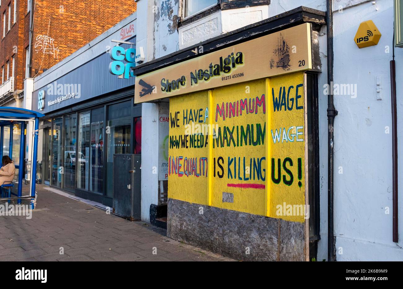 Negozio vuoto di fronte in High Street con slogan salariale minimo - Shoreham-by-Sea , Sussex , Inghilterra UK Foto Stock