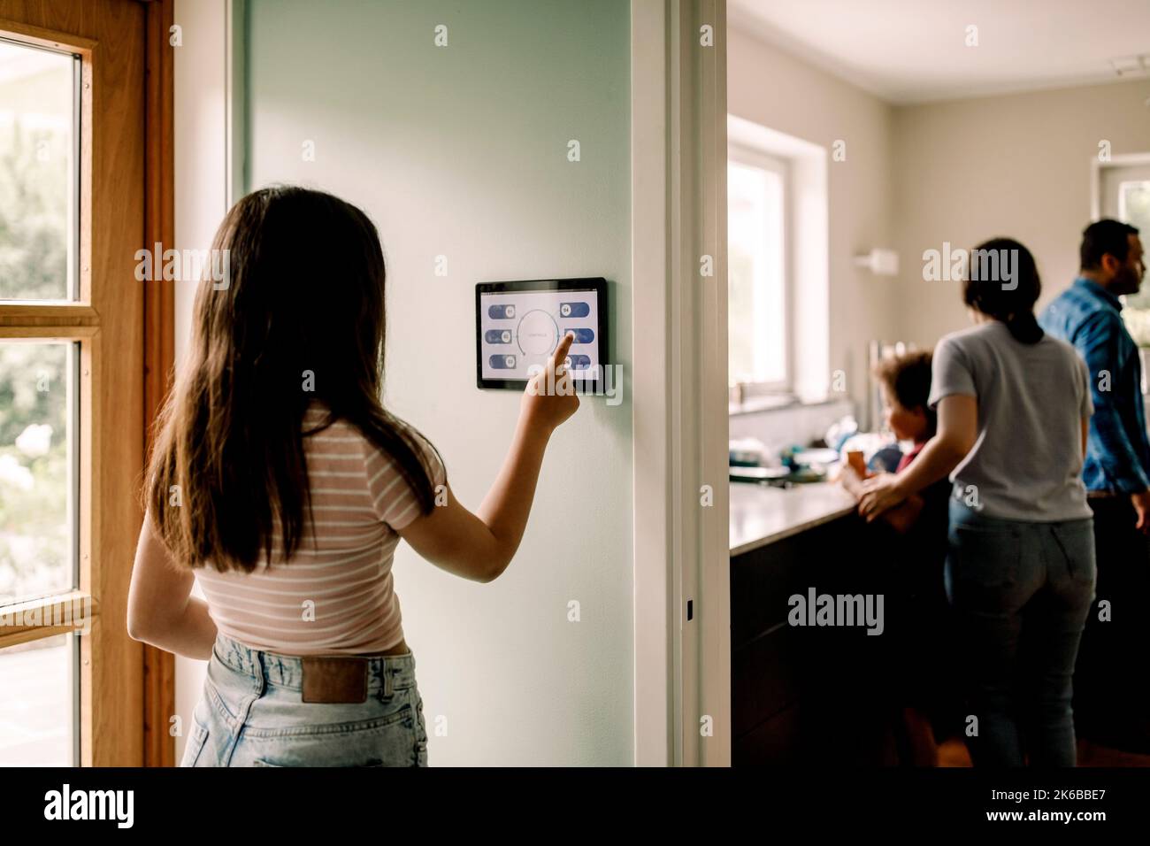 Ragazza che utilizza l'app Smart Home sul tablet digitale mentre si trova vicino alla porta Foto Stock