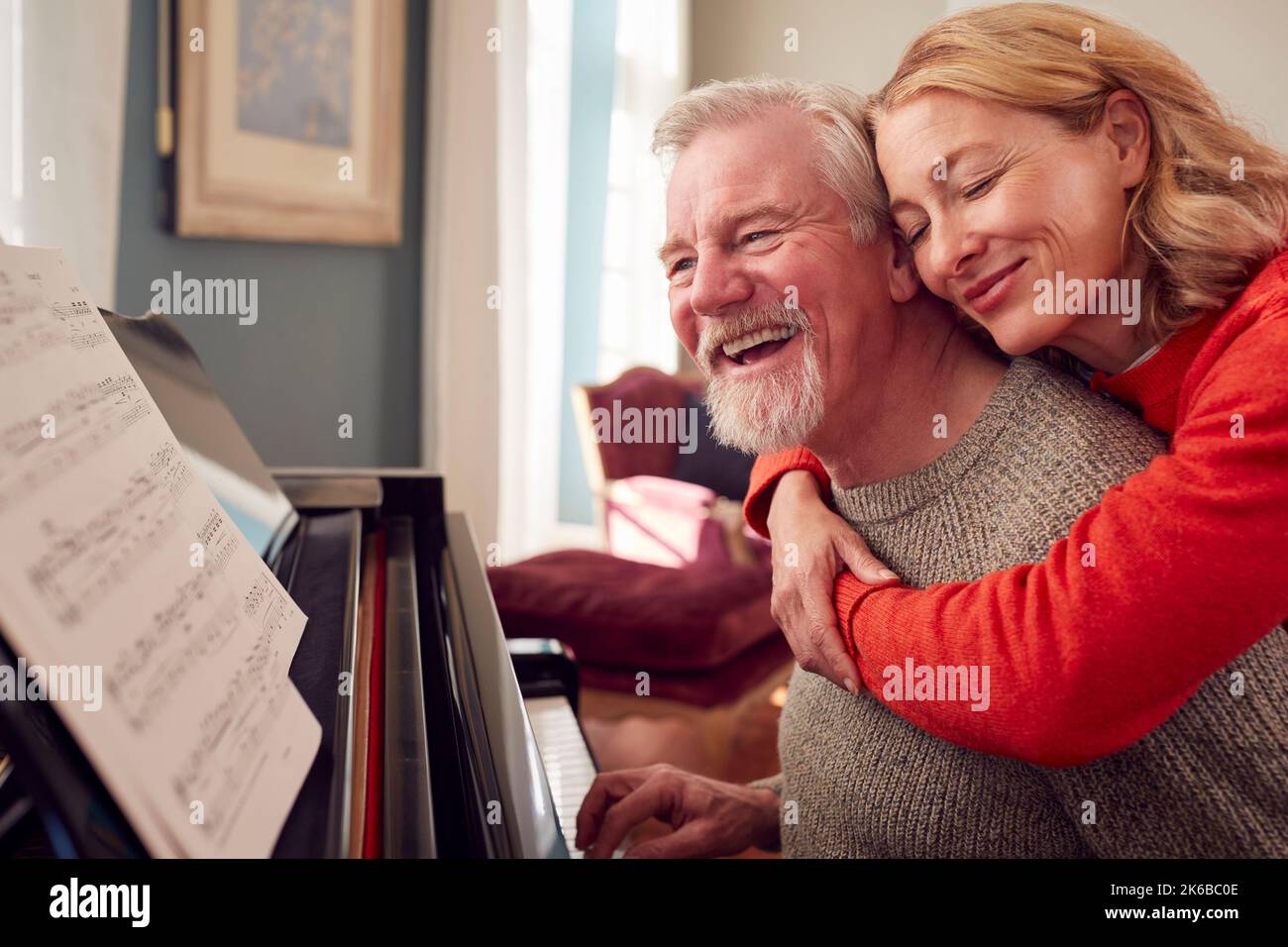 Coppia sorridente anziano a casa godendo imparare a suonare il piano Foto Stock
