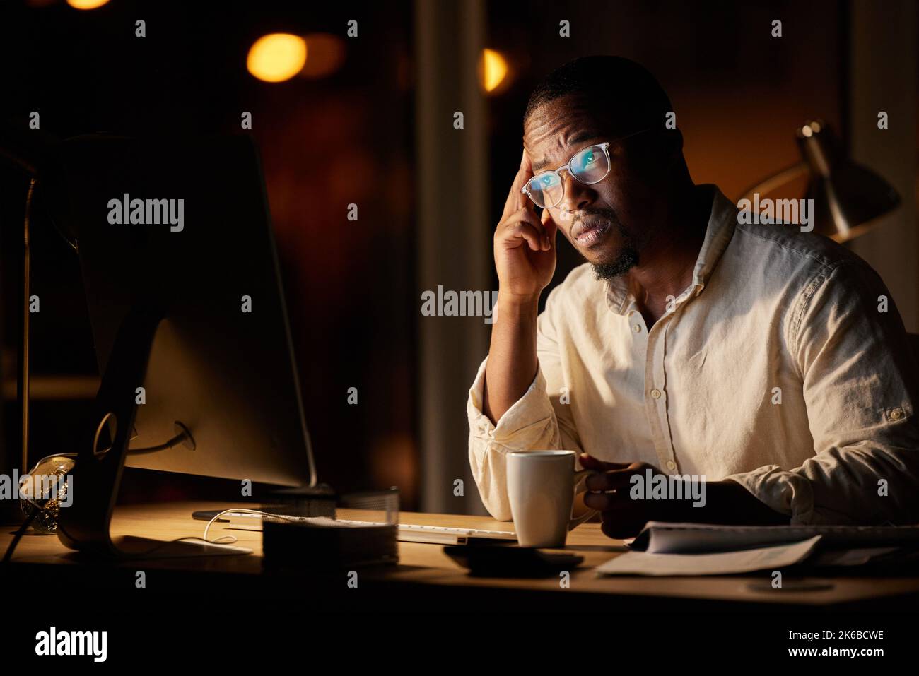 Im preoccupato che questa potrebbe essere la decisione sbagliata... un giovane uomo d'affari che guarda preoccupato mentre beve il caffè e lavorando su un computer in un ufficio a. Foto Stock