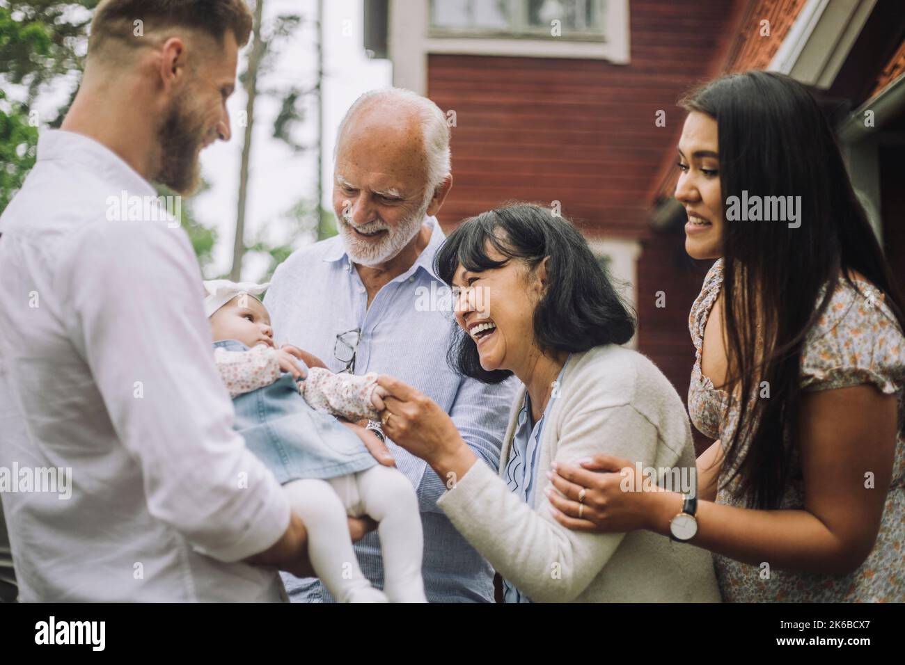 Felice famiglia multirazziale giocando con la bambina alla festa di cena Foto Stock