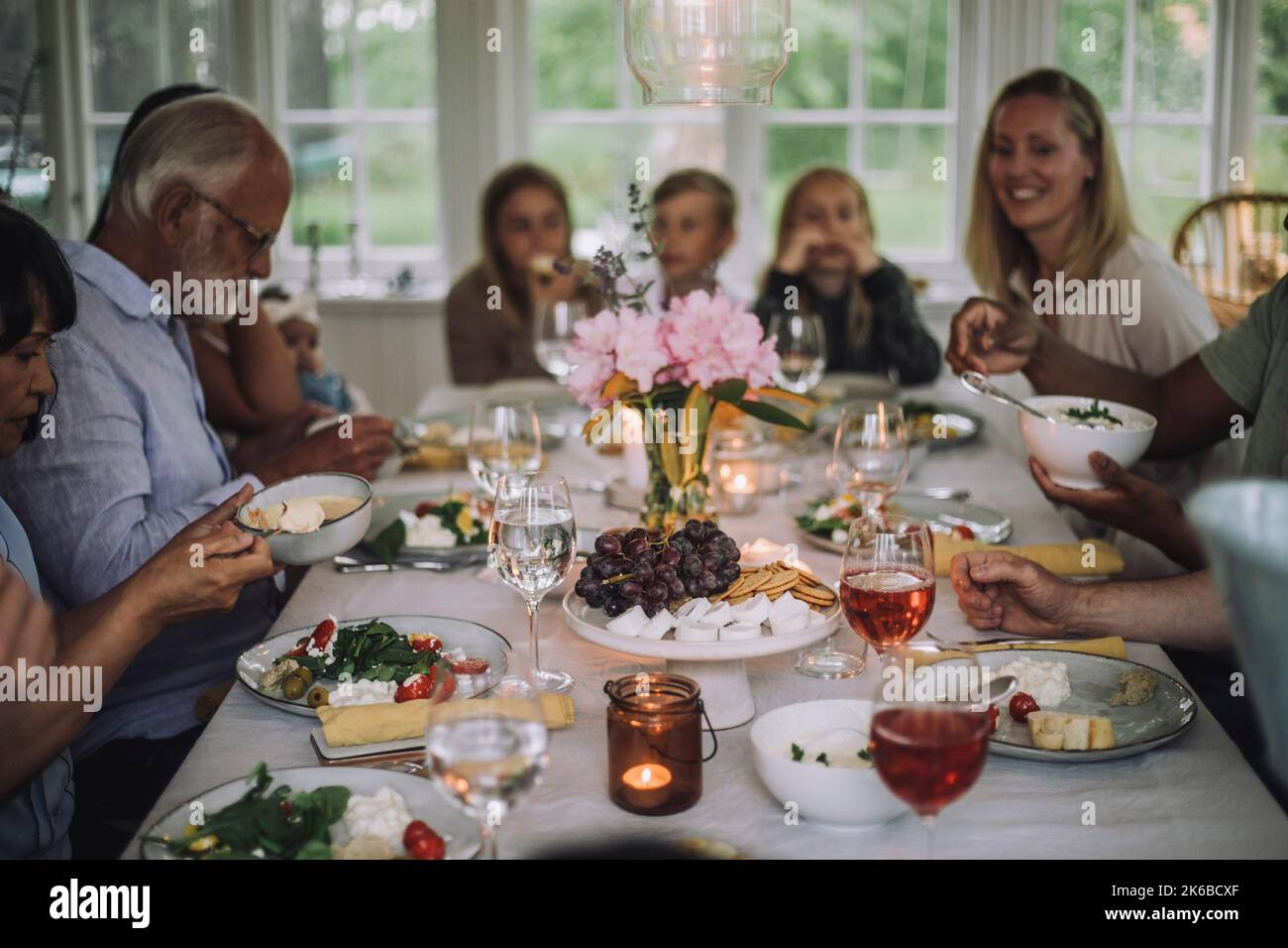 Famiglia di generazioni diverse che si gode la cena sul tavolo durante la festa a casa Foto Stock