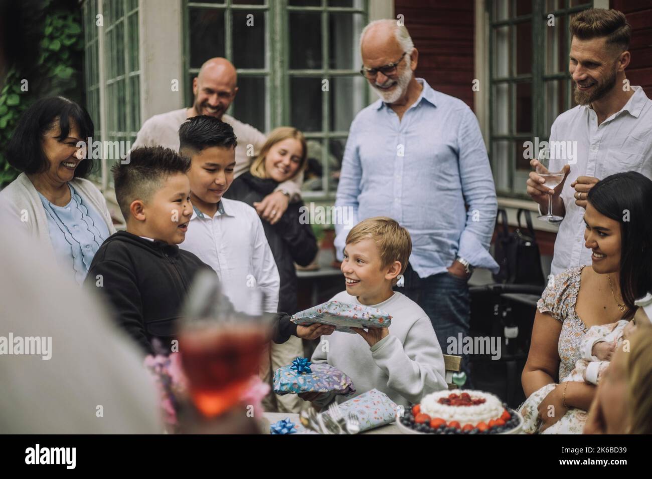 Ragazzo sorridente che riceve un regalo da un amico maschio durante la celebrazione del compleanno Foto Stock