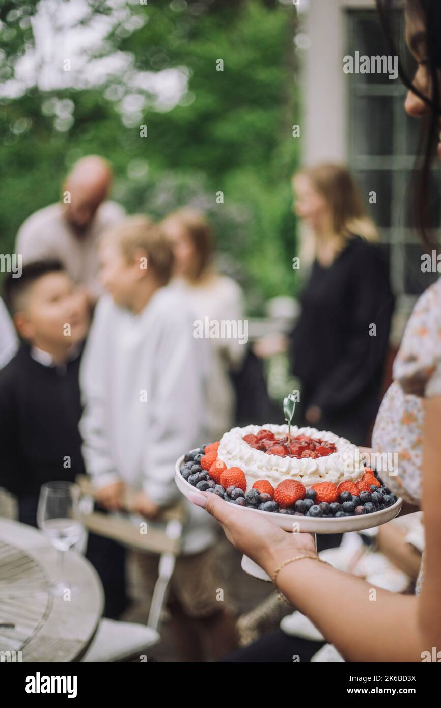 Donna che tiene torta di frutta fresca durante la celebrazione del compleanno Foto Stock