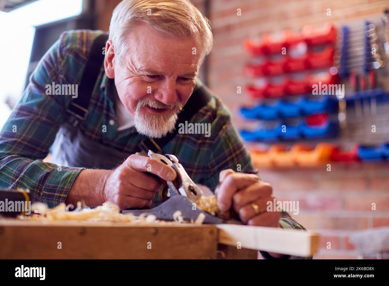 Falegname Senior maschio in officina Garage piallatura pezzo di legno Foto Stock