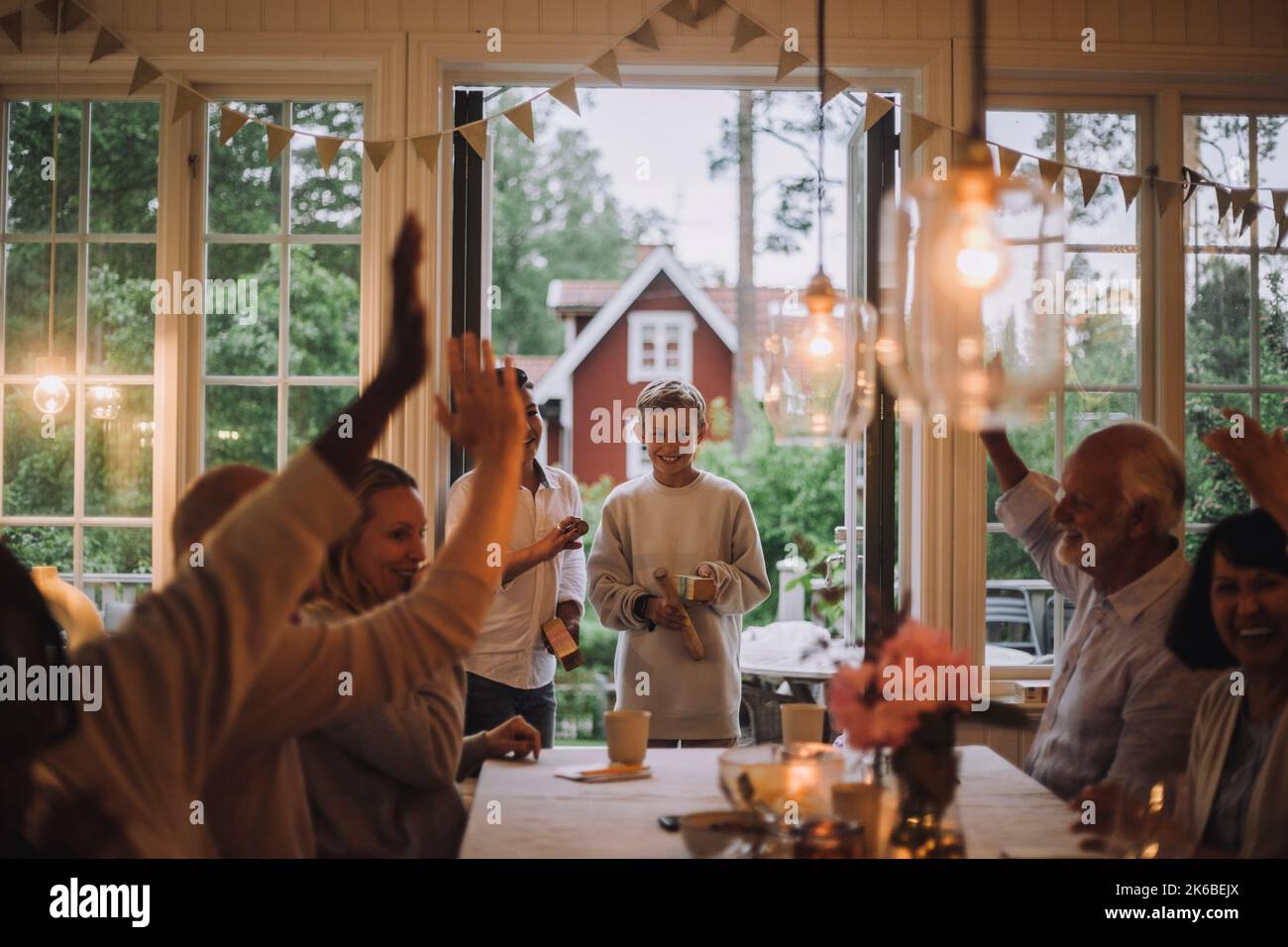 Famiglia felice con le mani alzate che si divertono mentre gioca durante la festa a casa Foto Stock
