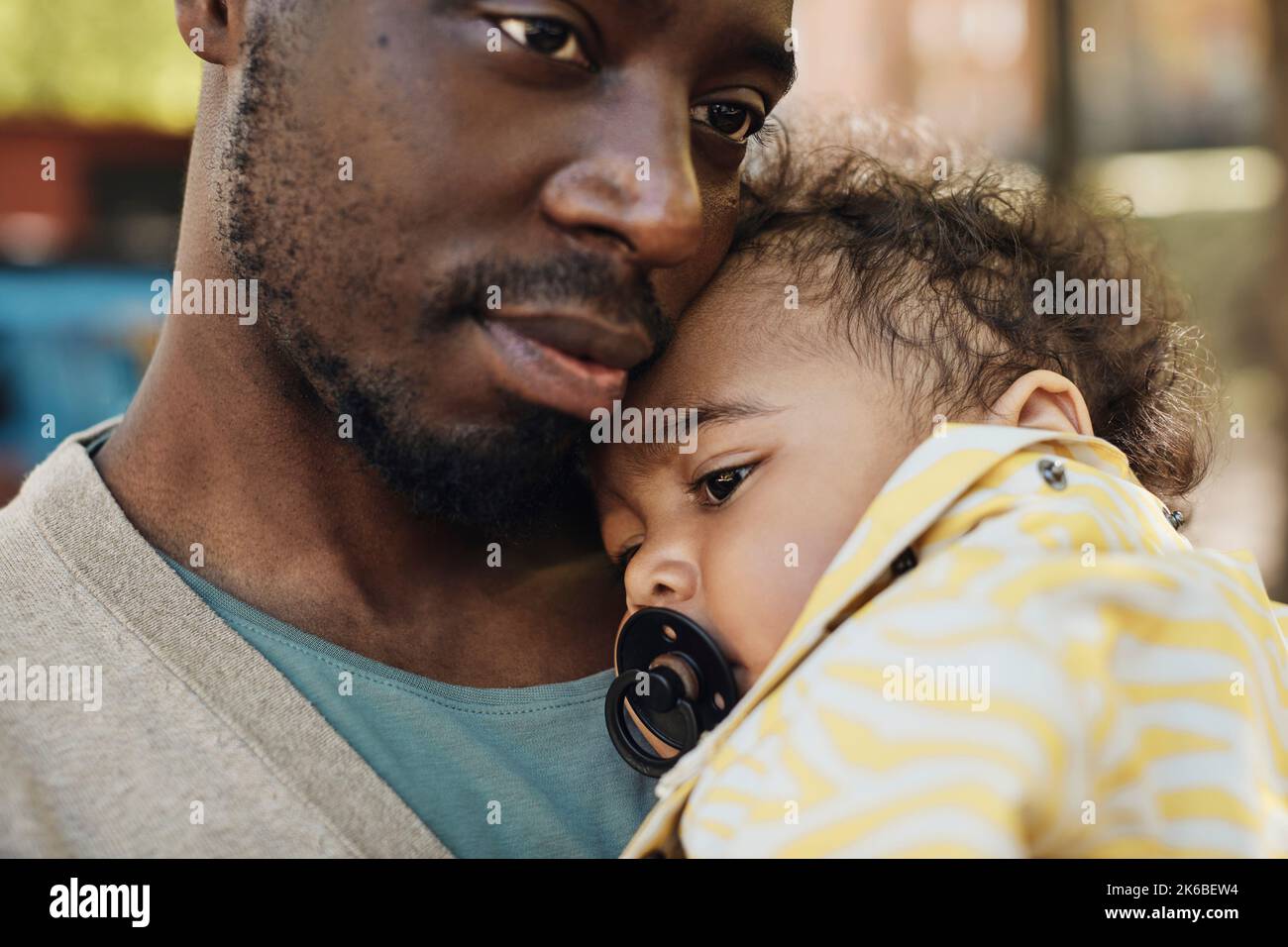 Padre che porta il bambino con il succhietto in bocca Foto Stock