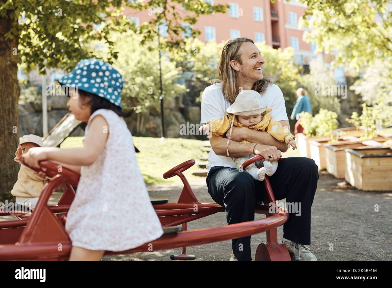 Felice padre che guarda via mentre si siede e si gode con la figlia in asilo Foto Stock